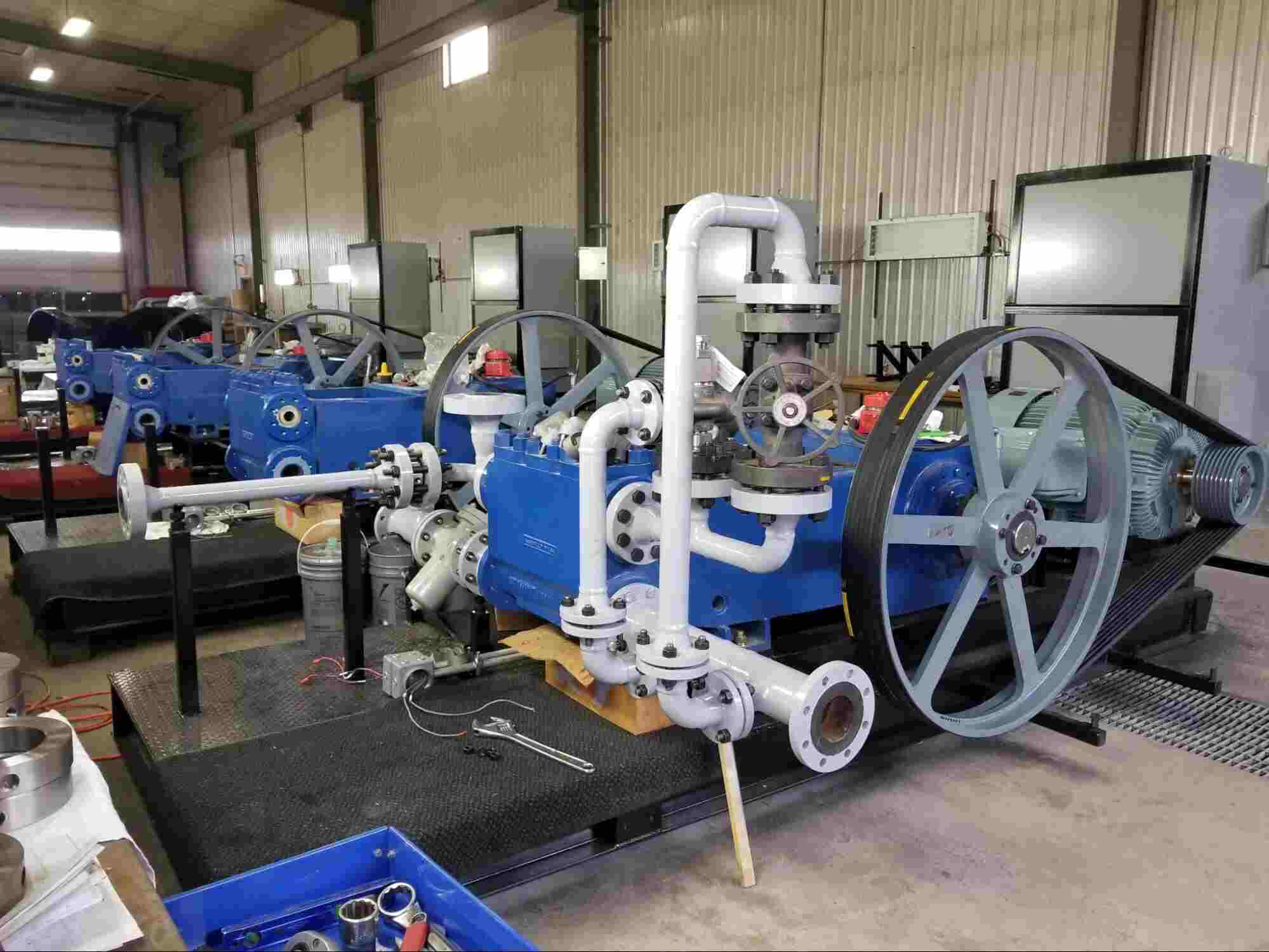 Industrial setup showcasing types of centrifugal pumps with large mechanical pump systems and piping in a workshop environment.